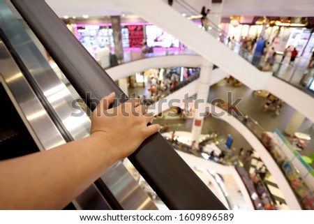 Asian woman's hand holding the escalator handrail.