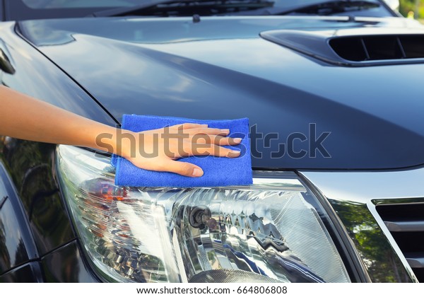 Asian woman\'s hand wiping surface of car by micro\
fiber cloth.