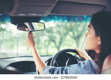 Asian women are adjusting the rearview mirror of the car - Powered by Shutterstock