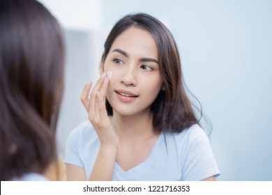 Asian Women Applying Face Lotion.