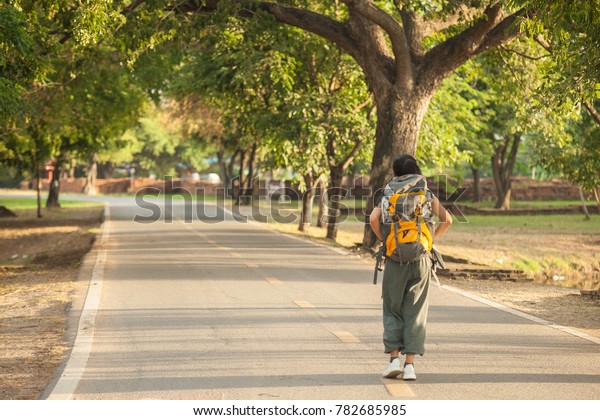 Asian women backpacker travel Ayutthaya\
Thailand, She walk on the long road to see around the old temple\
and waiting the card for the next plan to travel\
