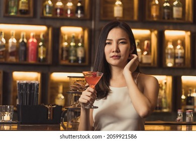 Asian Women Drinking Cocktails And Having Fun At The Bar At Night.