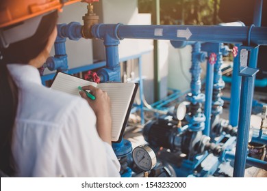 Asian Women Engineer Wearing Glasses Working In The Boiler Room,maintenance Checking Technical Data Of Heating System Equipment

