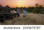 Asian women and European men on safari game drive in South Africa Kruger national park. a couple of men and women on safari. Tourists in a jeep looking sunset with drinks on safari