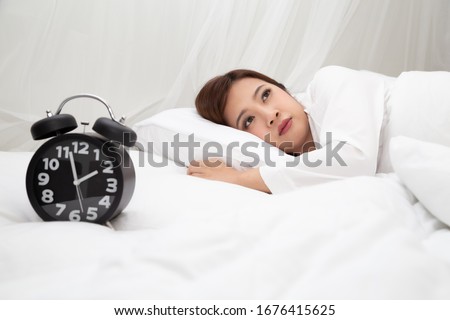 Asian women with feelings of helplessness and hopelessness on white bed in bedroom, Either insomnia, Depression symptoms and warning signs concept