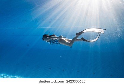 Asian women free diver alone in the depths pool. Swimmer brunette diving deep in ocean on blue underwater background. Asian women swimming underwater. - Powered by Shutterstock