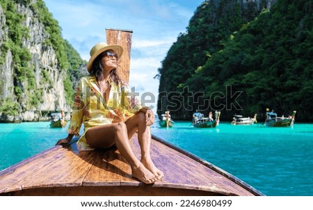 Asian women in front of a longtail boat at Kho Phi Phi Thailand, women in front of a boat at Pileh Lagoon