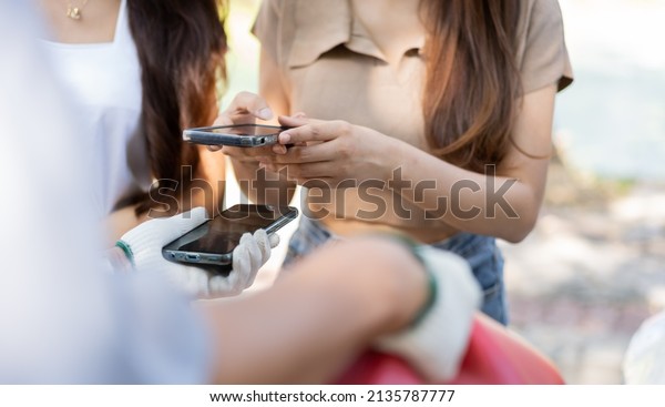 Asian women get contact numbers from Asian male\
auto mechanics after fixing the car engine problem and QR code scan\
to pay for fixing vehicle service. Car repair, and maintenance\
concept.