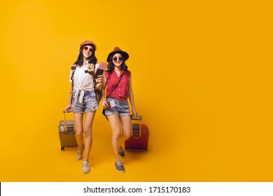 Asian Women Got Tickets To Travel Promotion On Summer, Two Young Girl Traveller Holding Suitcase And Passport For Travel In Studio.