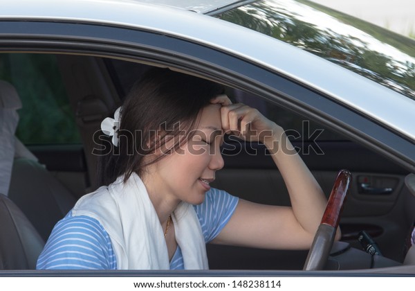 Asian women have a\
headache in the car.