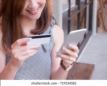 Asian women holding credit card and mobile phone in her hand with smiling face. Online shopping, e-commerce concept