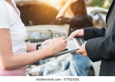 Asian Women And Insurance Agent Examining Car After Accident