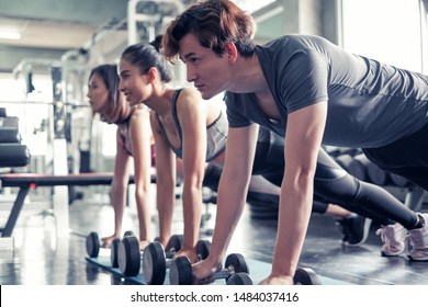 Asian women and man working out at gym center push up exercise with dumbbell