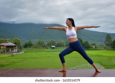 Asian Women Are Practicing Yoga To Become Physically Fit And Happy. In The Accommodation This View Is A Field.