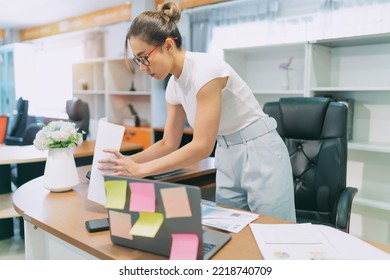 Asian Women Quit And Quiet On Business Work. Busy Female Worker Working Overtime Try To Find Information On Paper Sheet And Sticky Notes On Table. Occupation Office Woman Overwork Alone At Workplace.