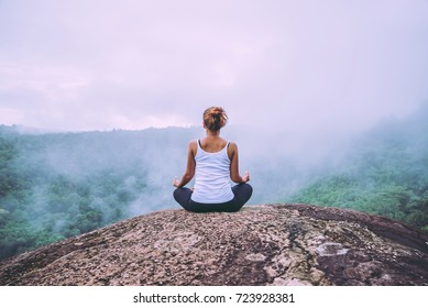 Asian women relax in the holiday. Play if yoga. On the Moutain rock cliff