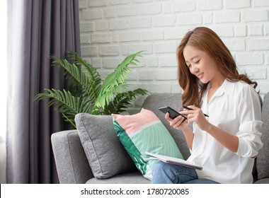 Asian Women Are Relaxingly Working At Home. She Using Phone To Contact People.