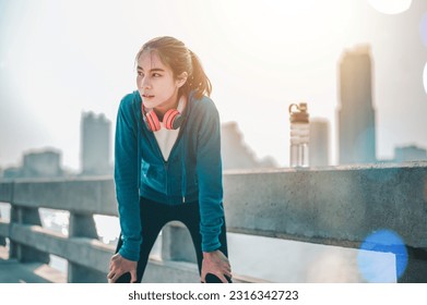 Asian women resting after a morning workout in the city. A city that lives healthy in the capital. Rear view of the city. Exercise, fitness, jogging, running, lifestyle, healthy concept. - Powered by Shutterstock