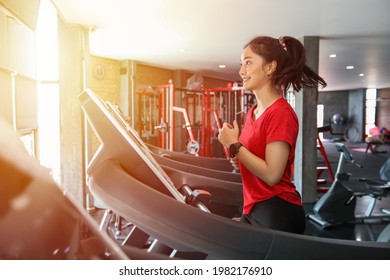 Asian Women Running Sport Shoes At The Gym While A Young Caucasian Woman Is Having Jogging On The Treadmill