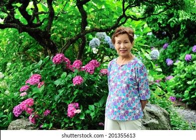 Asian Women In Senior Standing In The Garden Of Green