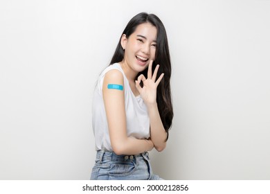 Asian Women Show Bandage On Arm. Happy Asian Woman Feels Good After Received Vaccine On White Background.
