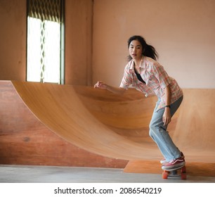 Asian Women Skater Doing Tricks Jumping In The Underground Garage. Urban Activity Indoor Lifestyle.