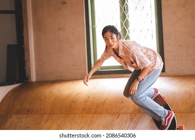 Asian women skater doing tricks jumping in the underground garage. Urban activity indoor lifestyle.