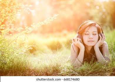 Asian women in summer with headphones listening to music and relaxing