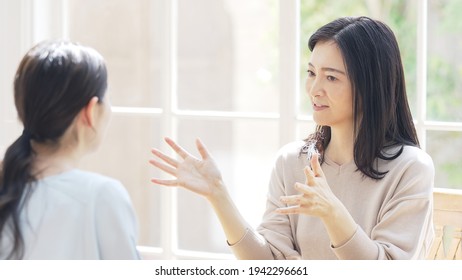 Asian women talking face to face.