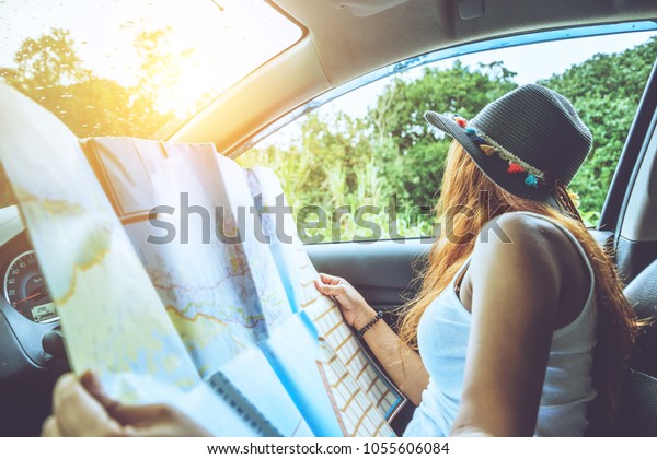 Asian women travel relax in the\
holiday. Traveling by car park. View map for travel. In the\
summer