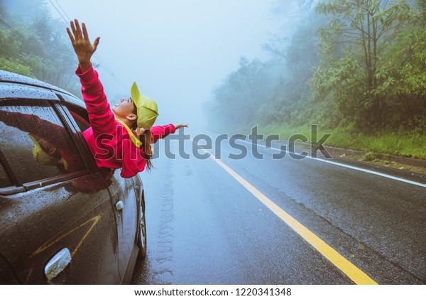Asian women travel relax in the
holiday. driving a car traveling happily. Amid the mist 
rainy.
