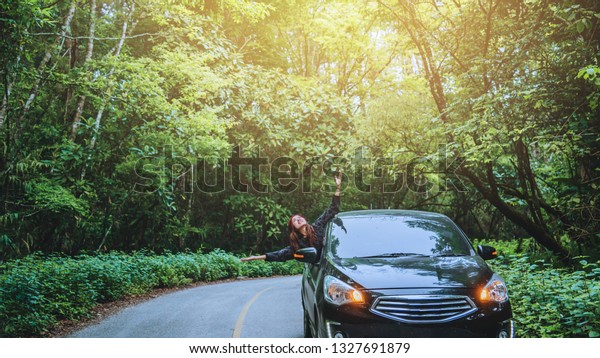 Asian women\
travel relax in the holiday. Traveling by car park. happily With\
nature, rural forest. In the\
summer