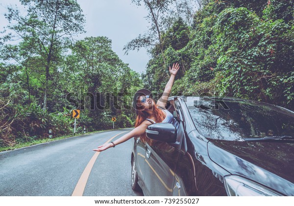 Asian women travel relax in the\
holiday. Traveling by car park. happily With nature, rural\
forest