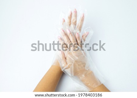 Asian women two hands wearing disposable plastic glove isolated on white background. Back view of hand in transparent gloves. Multipurpose glove protect hand sanitary food