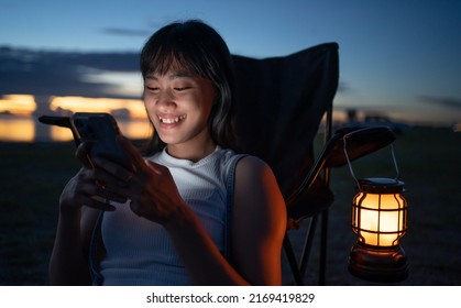 Asian Women Using Mobile Phone Communicate During Camping.young Japanese Girl Texting To Her Friend At Camping Outdoor Mountain At Night Time.