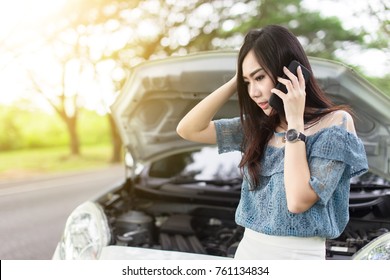 Asian women using a mobile phone call a car mechanic because car broken