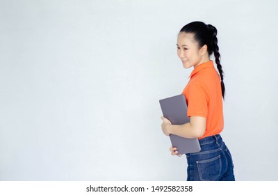 Asian Women Wear A Smiling Orange Shirt Carrying A Laptop Computer.Do Not Focus On Objects.