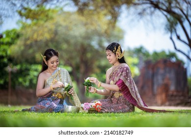 ิฺBeautiful asian women wearing thai dresses traditional they make white lotus garland on tray with pedestal for worship Buddha statue the in the temple.Buddhism religion worship believe concept