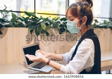 Asian women's business is cleaning hands with Alcohol gel in the workplace and wear mask protect pollution or corona virus