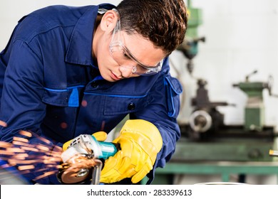 Asian Worker Grinding Metal In Manufacturing Plant, Sparks Flying As He Is Working On The Piece