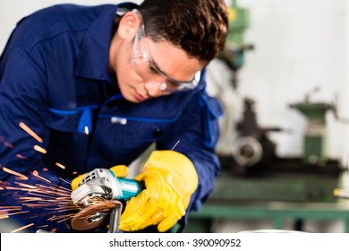 Asian Worker Grinding Metal In Manufacturing Plant, Sparks Flying As He Is Working On The Piece