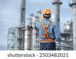 Asian worker power plant factory holding blueprint pointing check construction plan power plant. Engineer wearing safety uniform helmet at energy petrochemical industry.