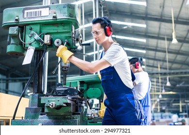 Asian Worker In Production Plant Drilling At Machine On The Factory Floor