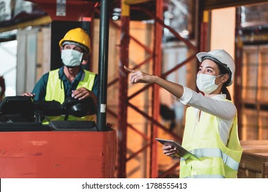 Asian Worker In Protective Face Mask Work In Warehouse Cargo. New Normal Working Concept In Industry, Factory, Inventory After Covid 19 Pandemic Outbreak 