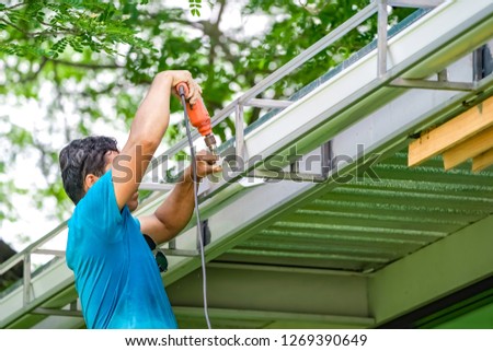 Asian worker screw, screwdriver to create and repair the rooftop water drain.