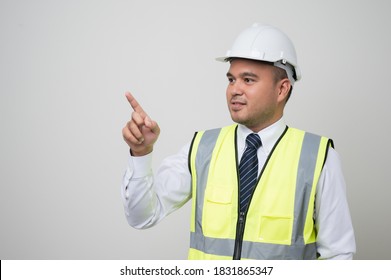 Asian Worker In Uniform Hard Hat Pointing The Finger To Blank Space For Advertise Text Or Mockup In Studio Isolated White Background.