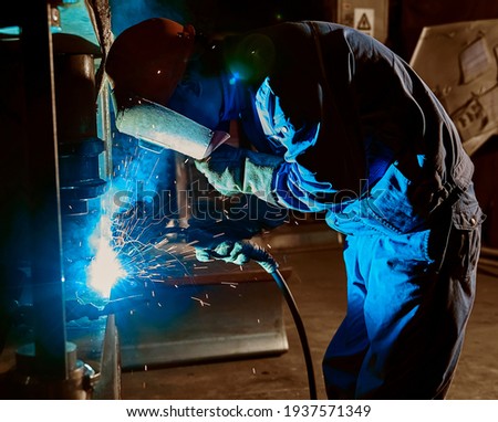Asian workers are hard welding iron plates in the factory