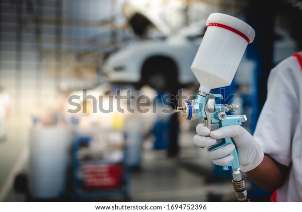Asian workers stand to\
hold a spray gun, antiseptic spray gun or car paint gun in\
protective clothing.