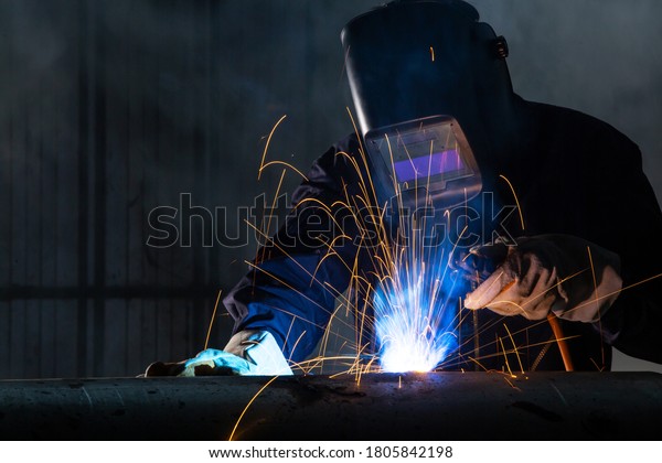 Asian\
workers wearing safety first uniforms and Welded Iron Mask at Steel\
welding plants, industrial safety first\
concept.
