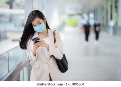 Asian working woman going to work and wearing hygienic masks or surgical mask prevent COVID-19 or coronavirus. She using a smartphone - Shutterstock ID 1757895584